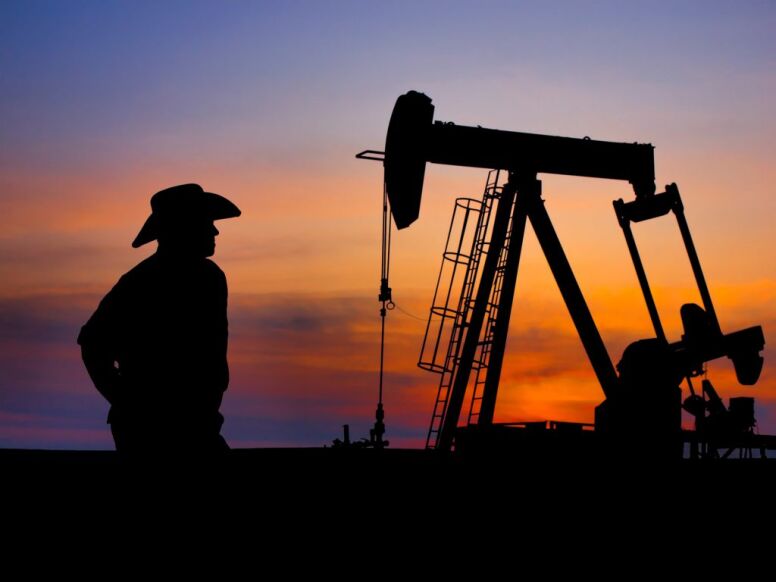 cowboy standing in front of oil pumpjack