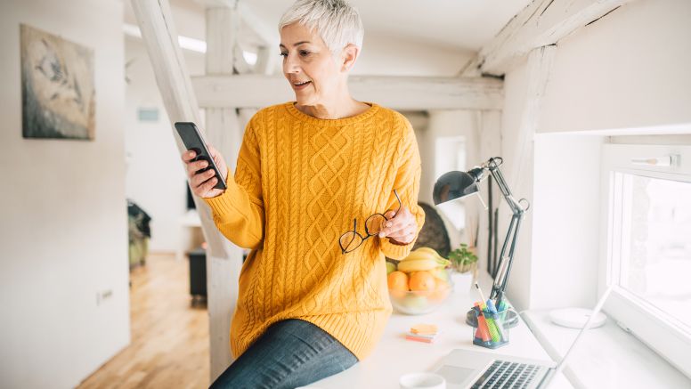Woman Looking At Phone In Home Office