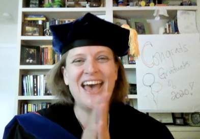Dr. Dickinson In Office With A Congrats Graduates Sign To Celebrate Students On Zoom Call