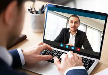 Pc screen view of videoconference over businessman shoulder
