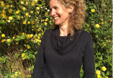 Jo Hand smiling in front of flowers