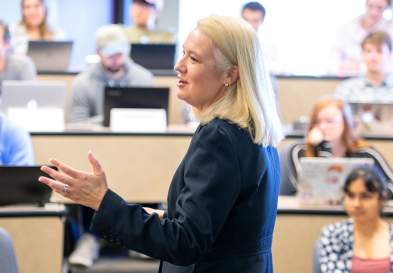 In a full classroom Claudia Kubowicz Malhotra speaking