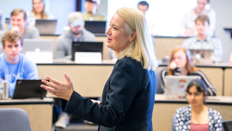 In a full classroom Claudia Kubowicz Malhotra speaking