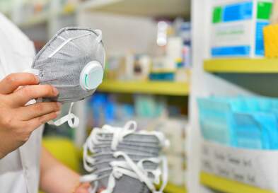 Healthcare worker hand holding N95 mask in pharmacy