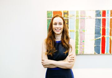 Paige Ouimet smiling standing in front of UNC Kenan-Flagler McColl art