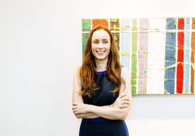 Paige Ouimet smiling standing in front of UNC Kenan-Flagler McColl art