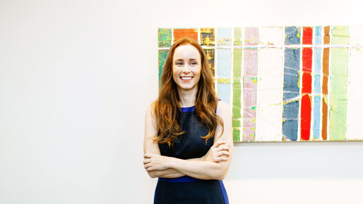 Paige Ouimet smiling standing in front of UNC Kenan-Flagler McColl art