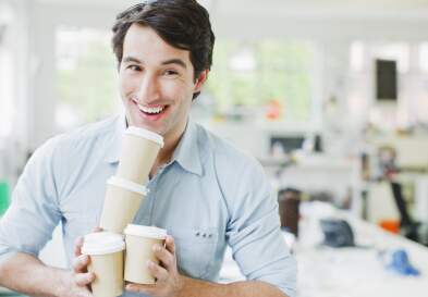Smiling businessman balancing coffee cups
