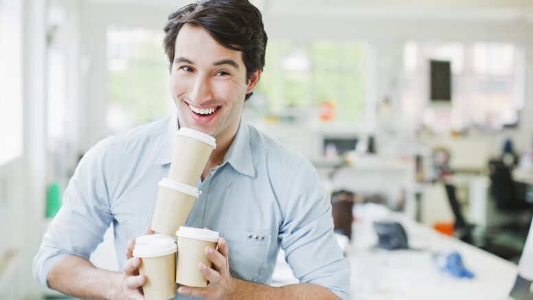 Smiling businessman balancing coffee cups