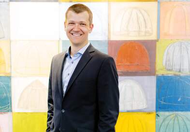 Kristopher Keller In McColl building standing in front of art at UNC Kenan-FLagler