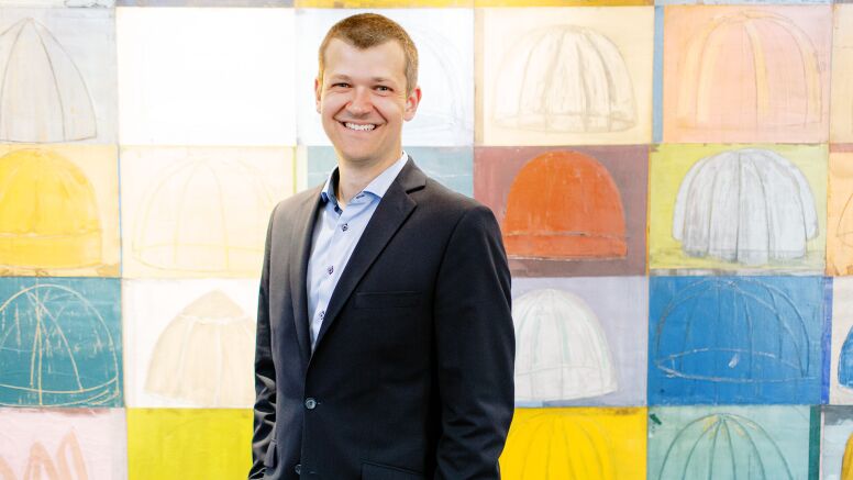 Kristopher Keller In McColl building standing in front of art at UNC Kenan-FLagler