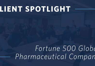 A graphic showing the words “Client Spotlight: Fortune 500 Global Pharmaceutical Company” overlaid on an image of businesspeople sitting around a conference table during a presentation.