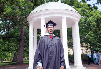 MAC graduate stands in front of the Old Well