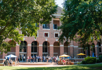 McColl Building with students in front gathered around tables outside