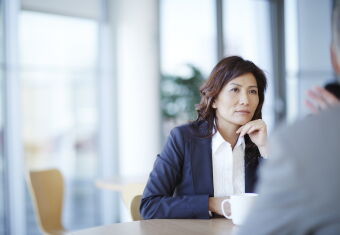 Businesswoman listening to colleagues speak during a meeting.
