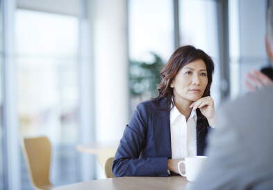 Businesswoman listening to colleagues speak during a meeting.