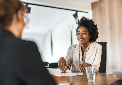 Two businesspeople talking across desk in a business meeting.