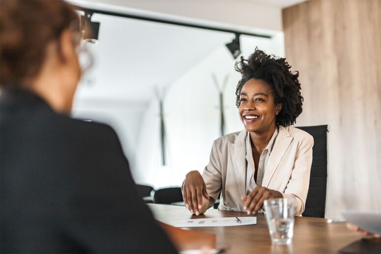 Two businesspeople talking across desk in a business meeting.
