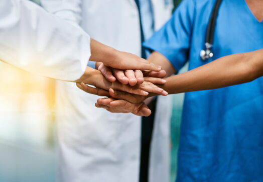 Shot of a group of unrecognisable medical practitioners joining their hands together in unity