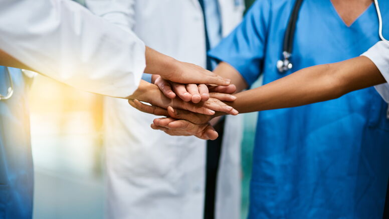 Shot of a group of unrecognisable medical practitioners joining their hands together in unity