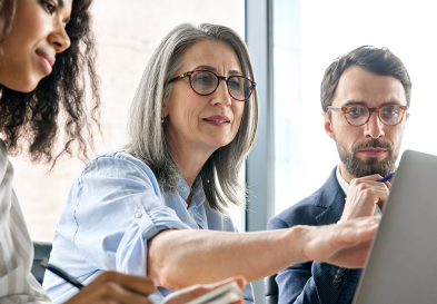 Three businesspeople looking at a laptop screen.