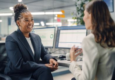 Two female businesspeople smiling in a one-on-one meeting.