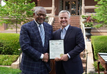 Professor Johnson and Governor Stein shake hands while holding the award.