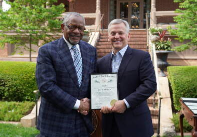 Professor Johnson and Governor Stein shake hands while holding the award.