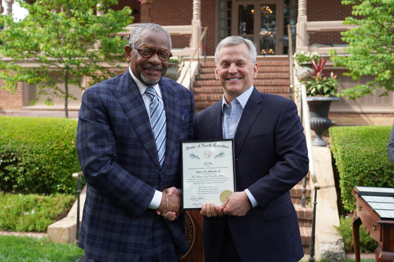 Professor Johnson and Governor Stein shake hands while holding the award.