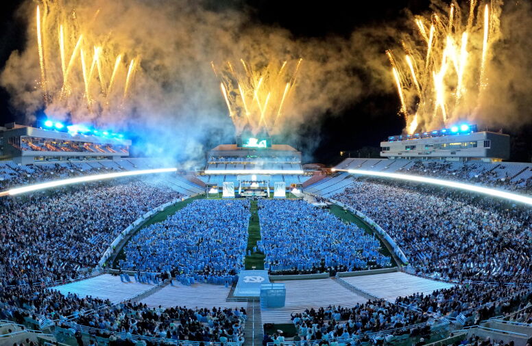 An overhead wide shot of spring commencement at Kenan Stadium with fireworks going off.