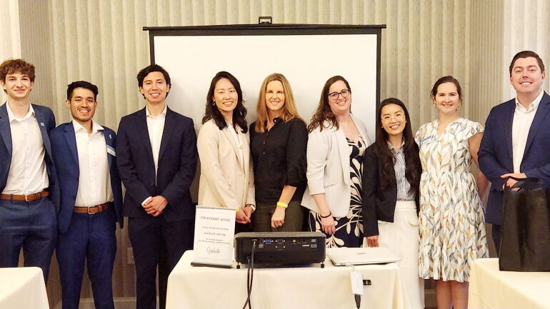 A group of students standing in a row smiling after completing a presentation