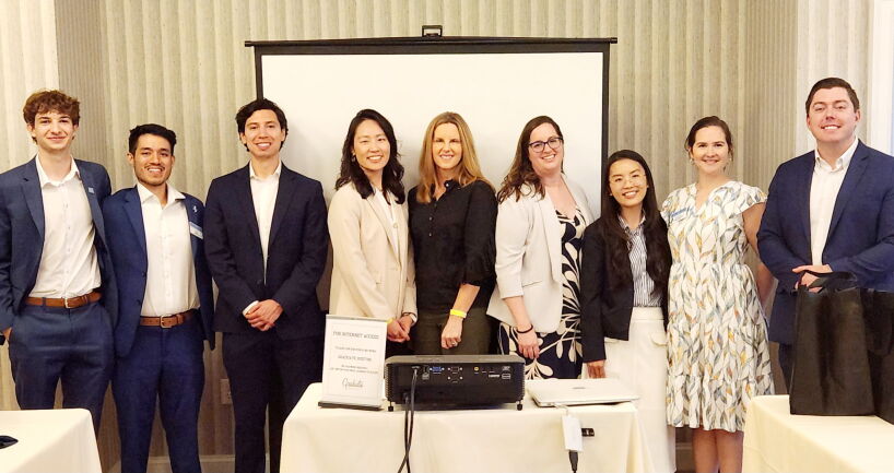 A group of students standing in a row smiling after completing a presentation