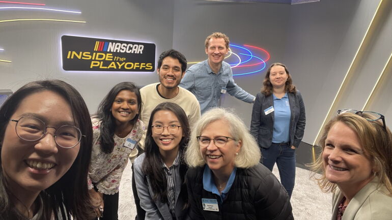 Seven students and a faculty member taking a group selfie on a company visit