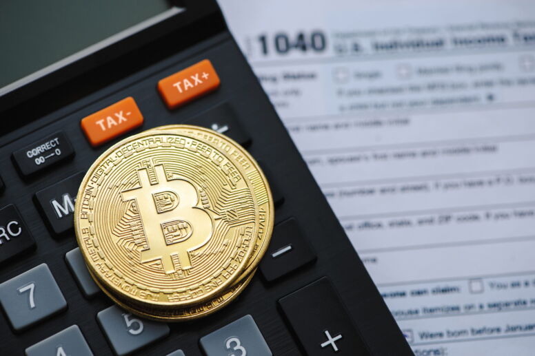 Bitcoin on top of a calculator and tax return.