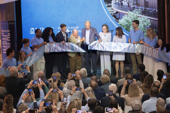 Steven D. Bell cuts a Carolina blue ribbon reading “Grand Opening Celebration!”