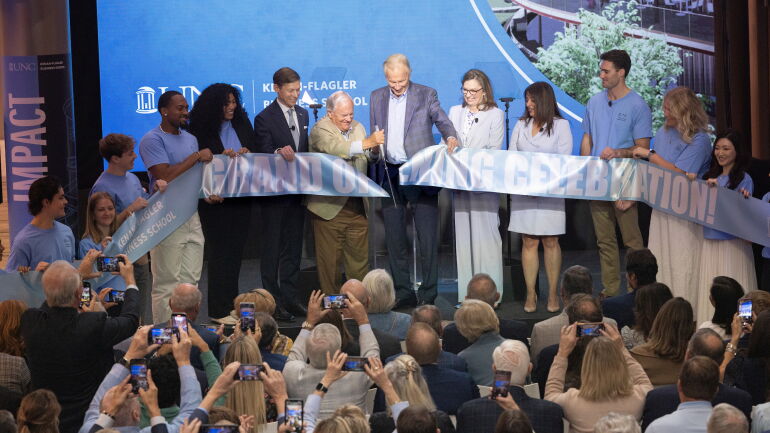 Steven D. Bell cuts a Carolina blue ribbon reading “Grand Opening Celebration!”