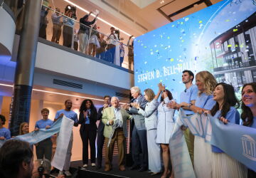 The group on the stage smiles and watches streamers fall after Steven D. Bell cut the ribbon for the grand opening of Bell Hall.