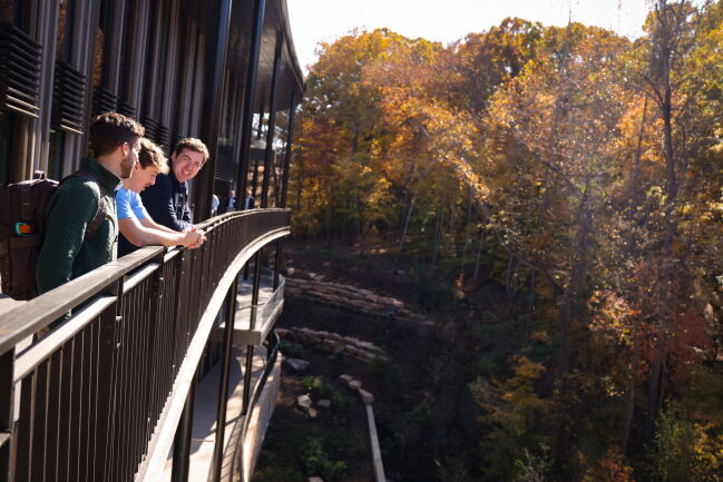 Three students overlook the landscaping surrounding Bell Hall from the walkway.