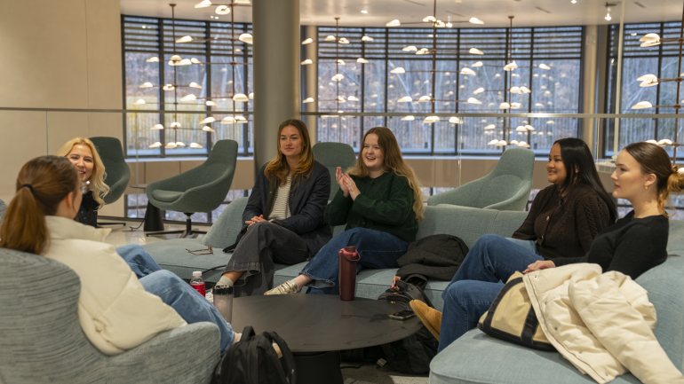 Students chat on couches in a common area in Bell Hall.