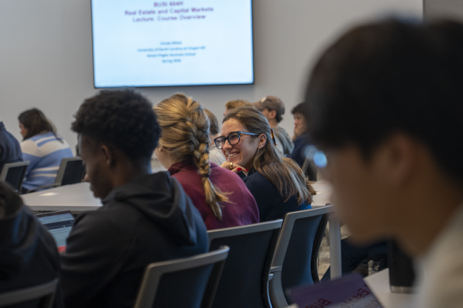 A student smiles in between classmates in a Bell Hall classroom.
