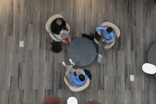 Three students sit at a circular table in Bell Hall, taken from above.
