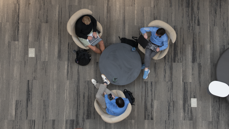 Three students sit at a circular table in Bell Hall, taken from above.