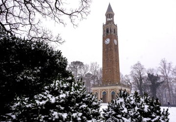 The Bell Tower framed by snow-covered greenery against a gray sky.