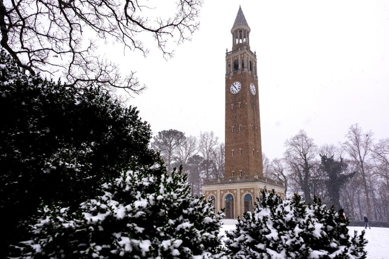 The Bell Tower framed by snow-covered greenery against a gray sky.
