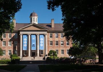 South Building set behind trees with UNC-branded banners hanging off of the front of it.