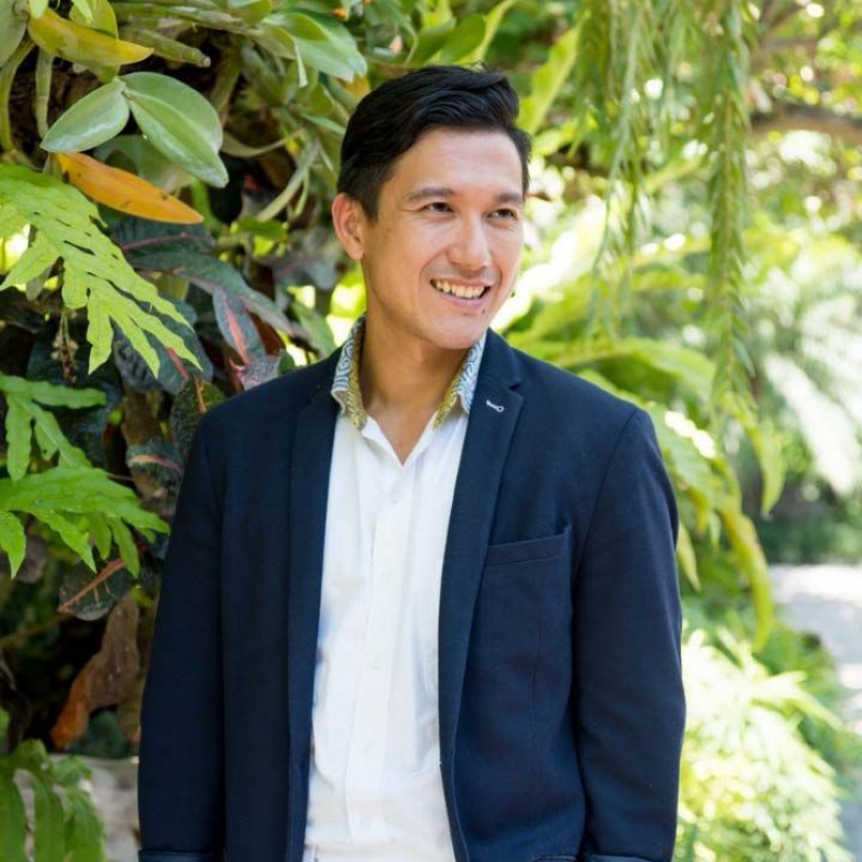 Jerry Winata standing in front of trees smiling