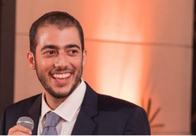 Guilherme Correa speaking into microphone and smiling