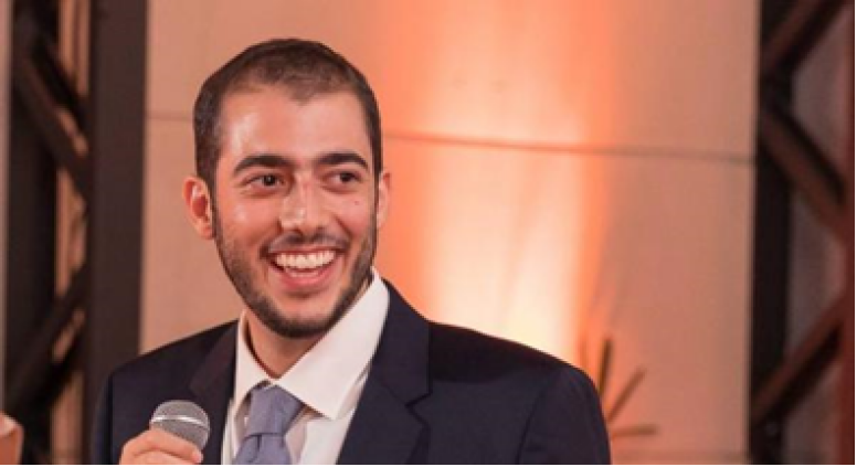 Guilherme Correa speaking into microphone and smiling