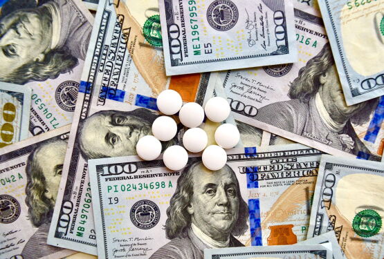 USA national currency, top view of mixed American dollars banknotes with white pills on it, drugs, money laundering, cartel, expensive medicine concepts. Top view