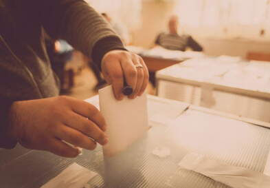 Man hands putting ballot in box